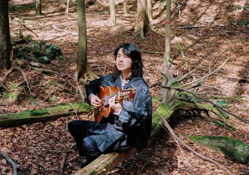森の中でギターを演奏するTatsuro Murakami